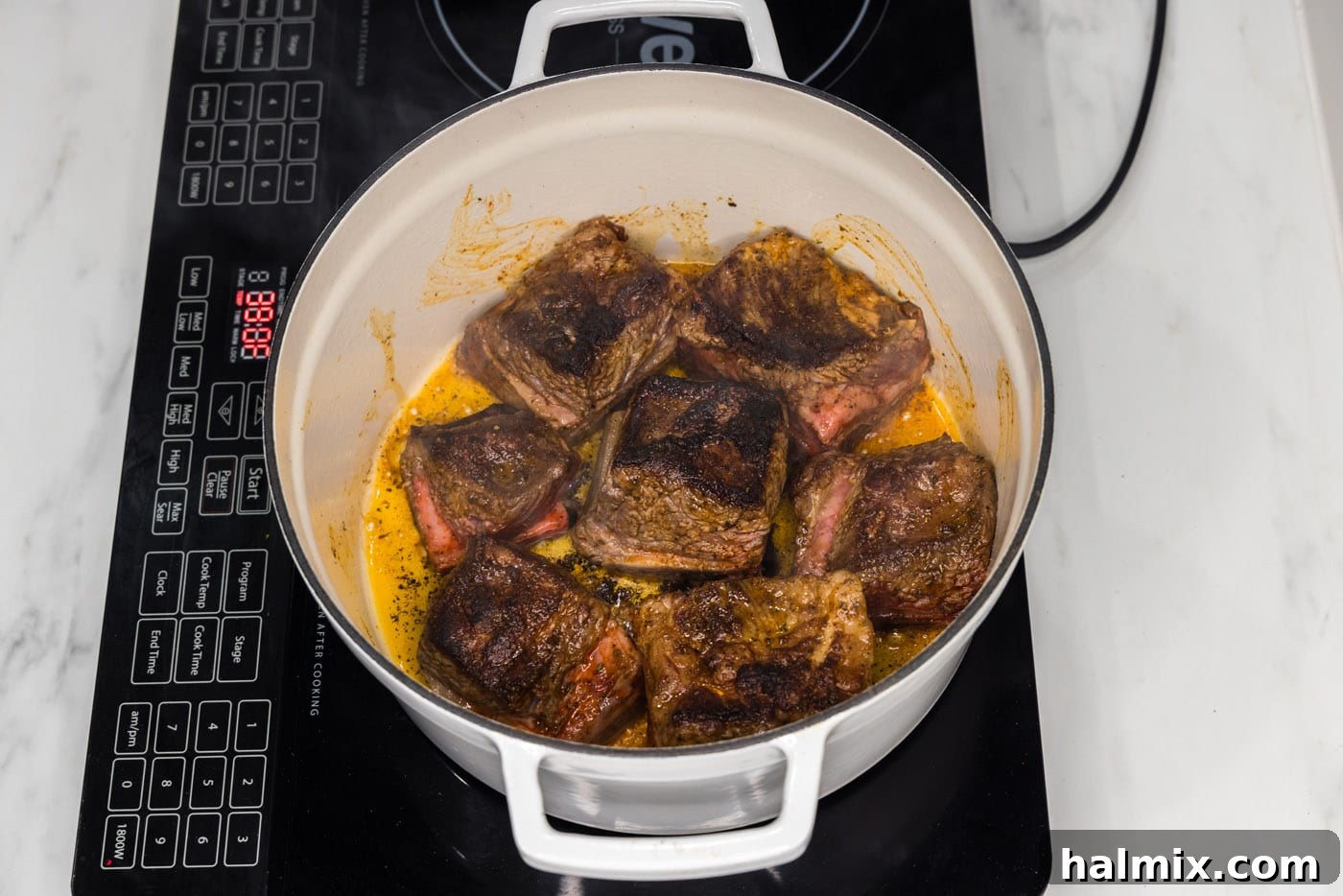 Perfectly seared short ribs, with a dark, caramelized crust, resting in a Dutch oven.