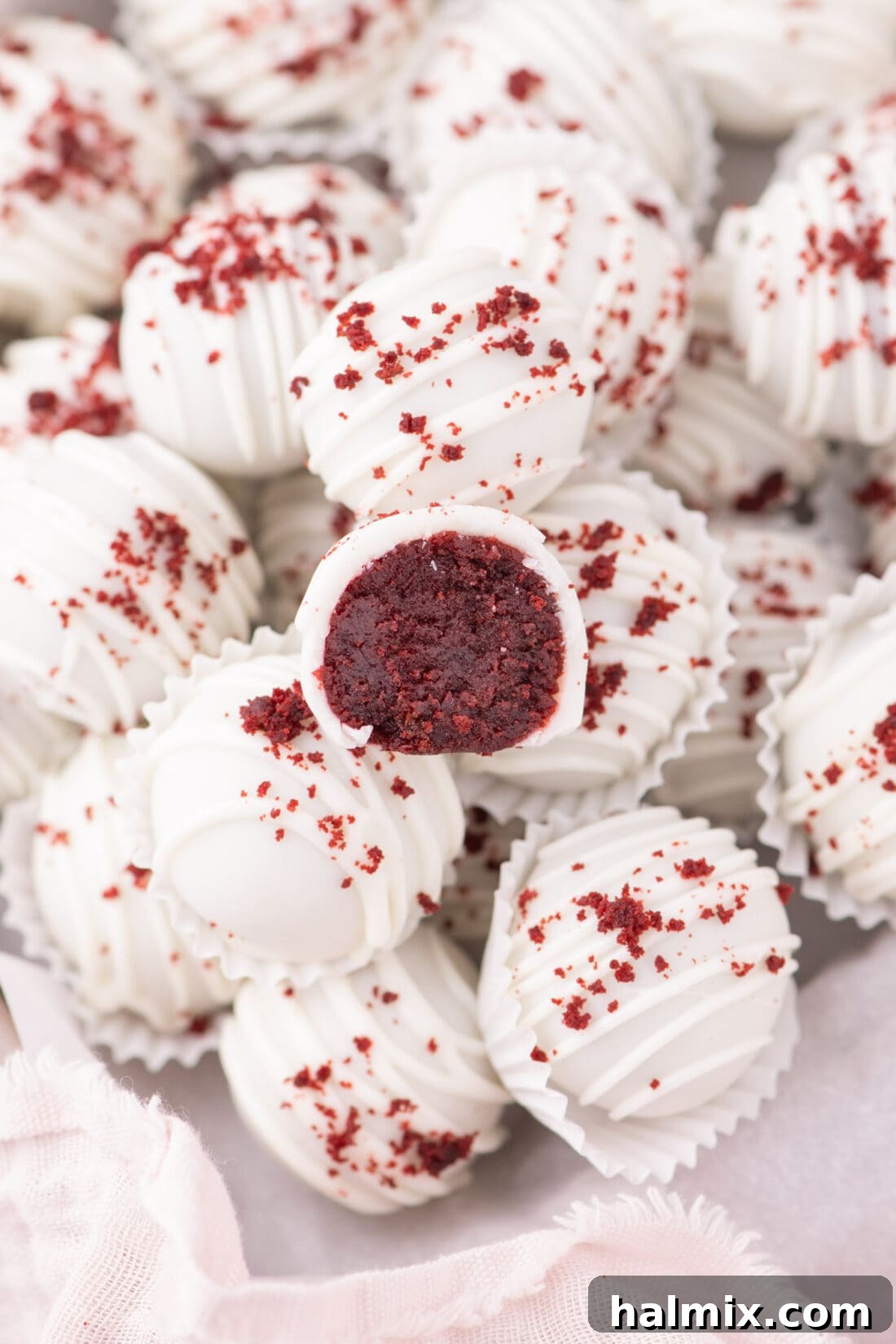 Half-cut Red Velvet Cake Ball showcasing its moist interior, resting on top of whole cake balls