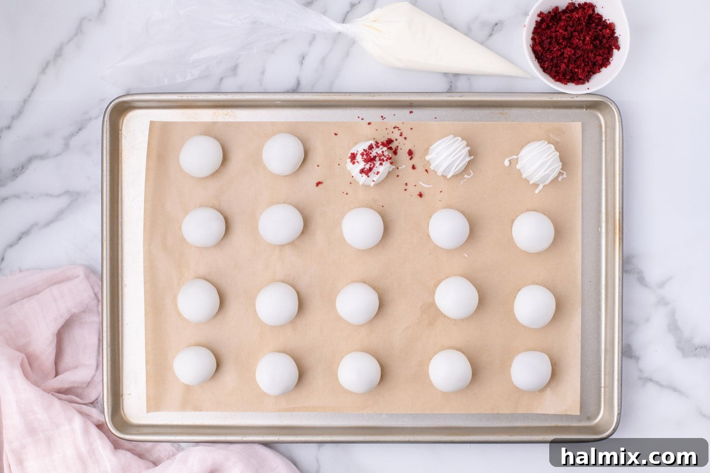 Sprinkling reserved cake crumbs on top of freshly drizzled red velvet cake balls