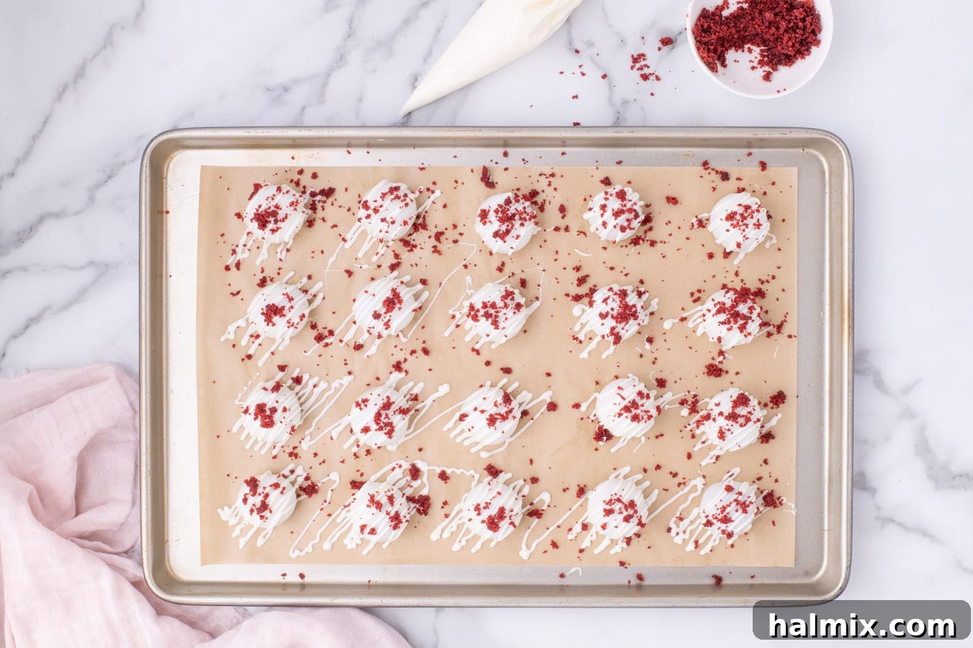 Overhead shot of completed red velvet cake balls drying on a baking sheet