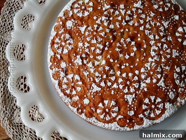 An overhead shot of a freshly baked Merryfield apple cake on a white platter, ready for dusting.