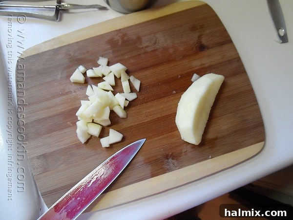 An overhead shot of fresh apples being skillfully chopped on a rustic wooden cutting board, ready for baking.