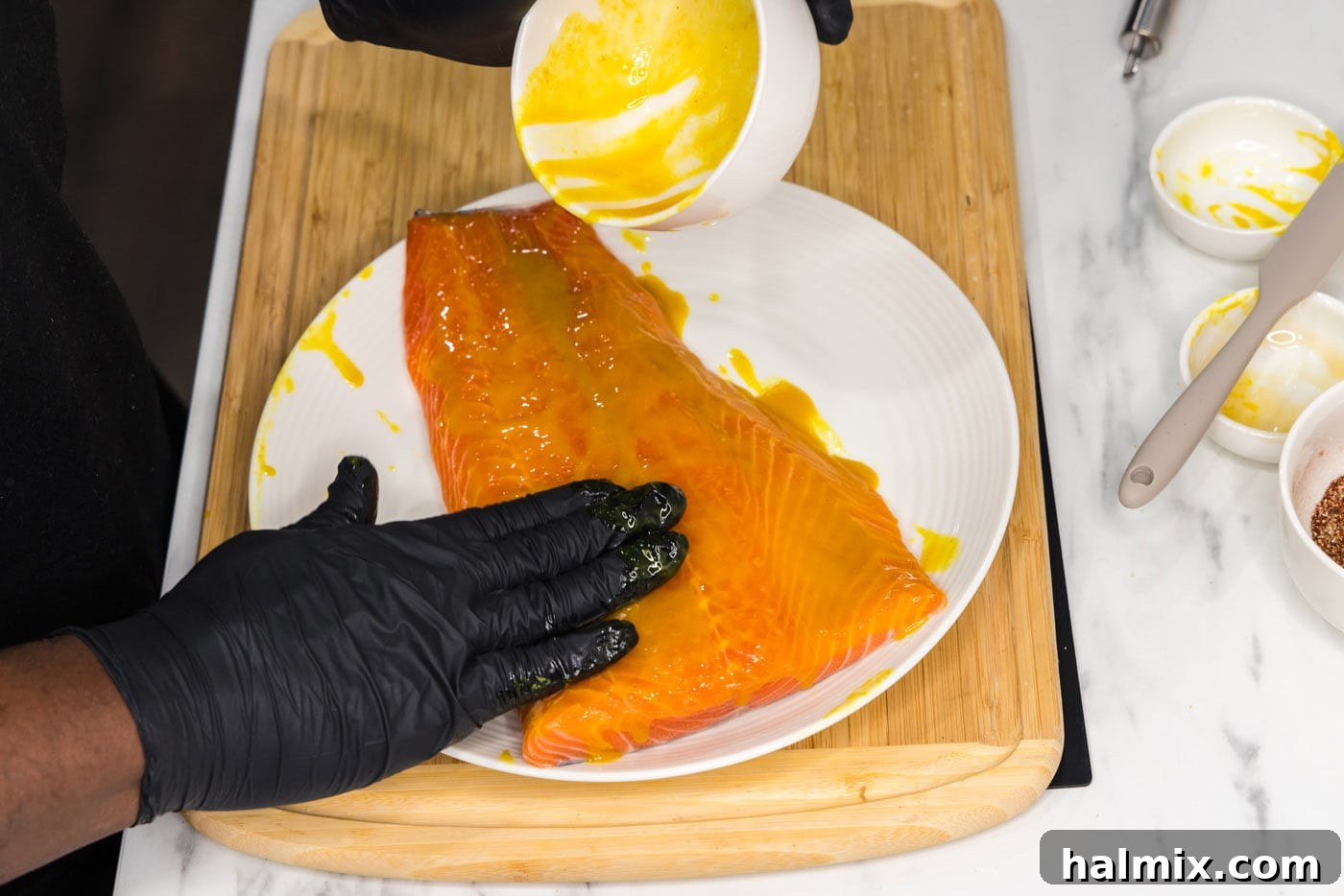 Chef rubbing a salmon fillet with a mustard and honey mixture