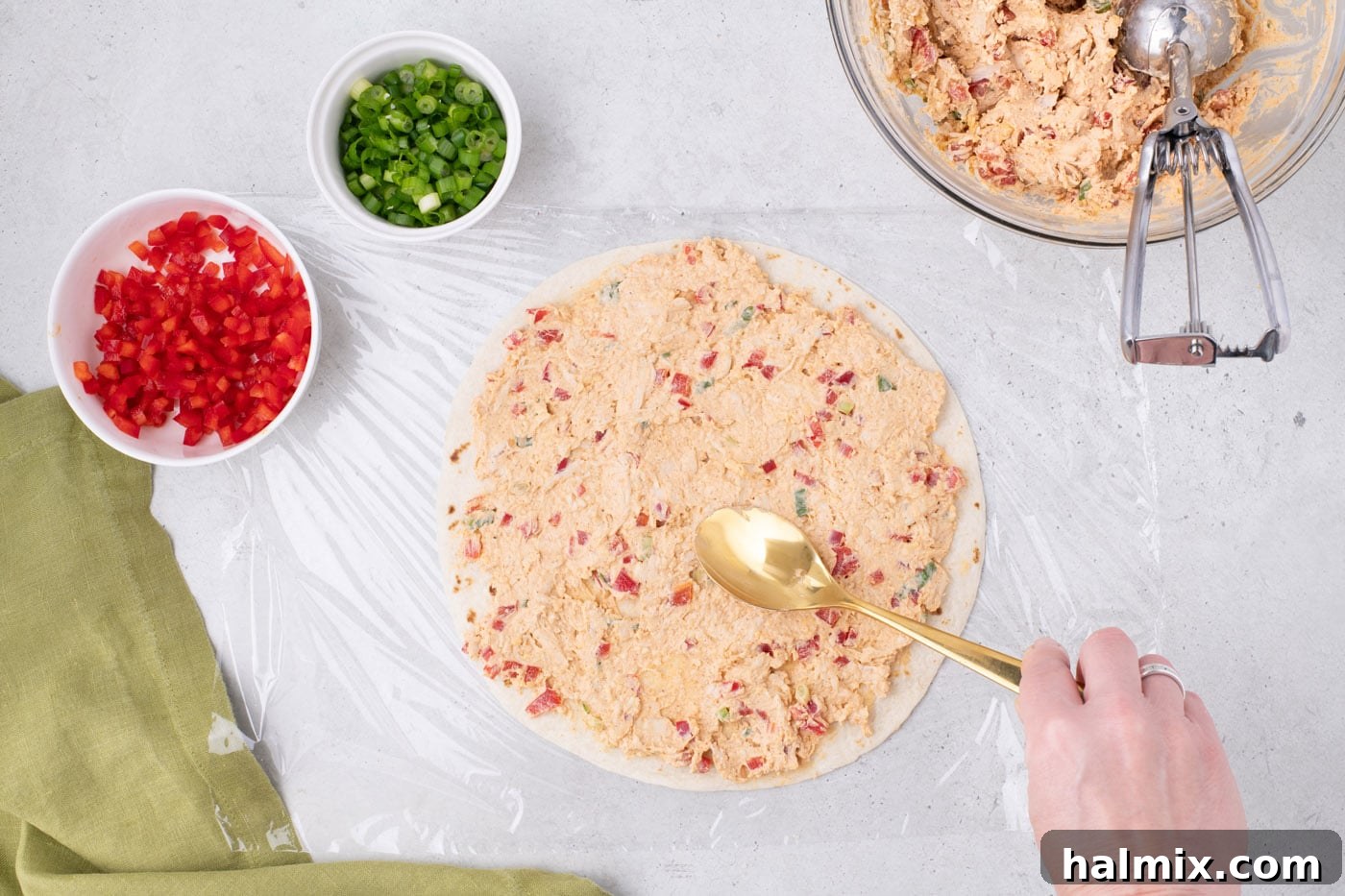 spreading cream cheese taco filling over a burrito tortilla shell