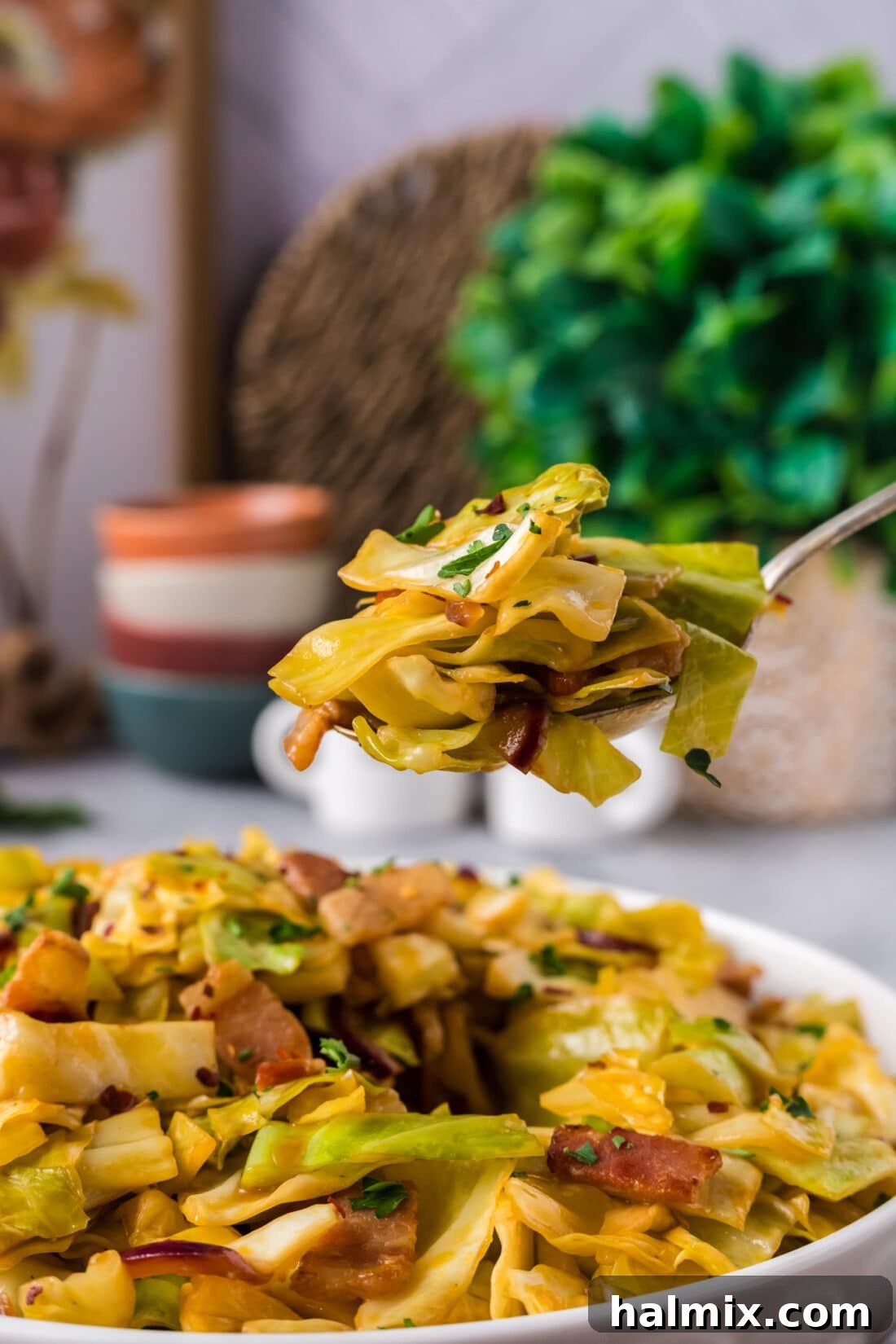 Fiery Fried Cabbage 3 Spoonful of Spicy Fried Cabbage held above a bowl of Spicy Fried Cabbage