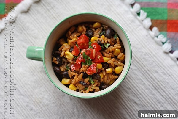 An inviting overhead view of Spanish rice with black beans and corn served in a beautiful teal and white bowl.