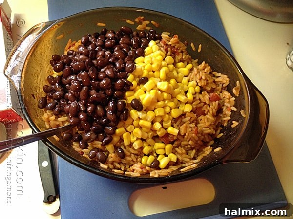 A bowl brimming with Spanish rice, black beans, and corn, showcasing the vibrant ingredients.
