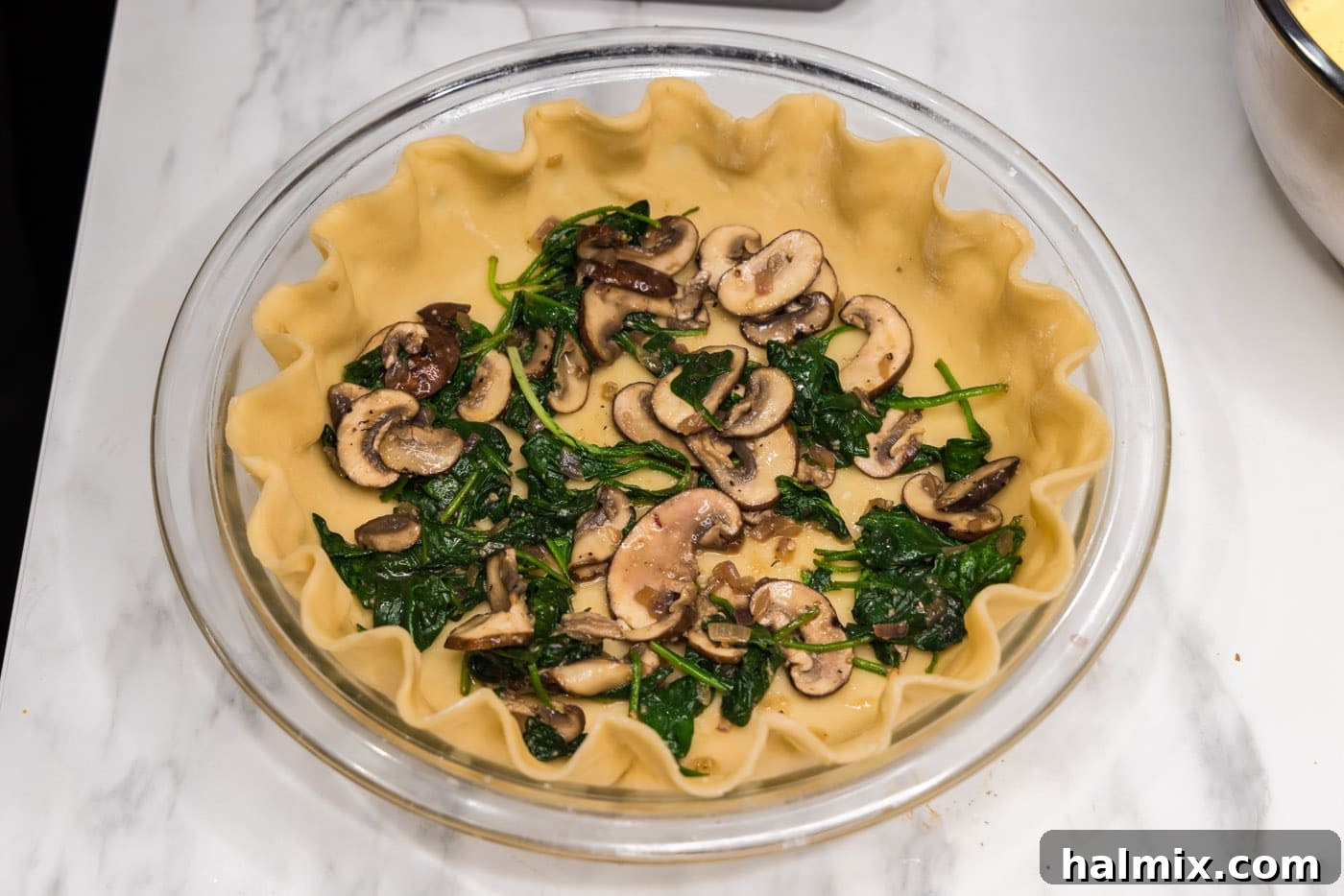 Half of the sautéed mushroom and spinach mixture spread evenly in the unbaked pie crust.