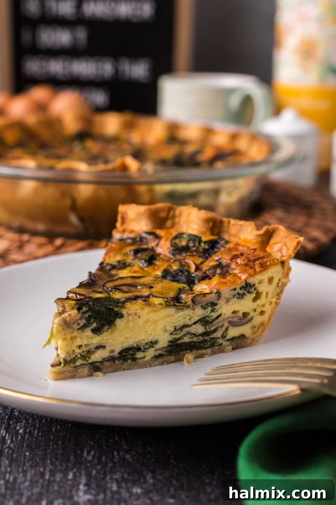 A perfectly cooked slice of Spinach Mushroom Quiche resting on a pristine white plate, garnished with fresh herbs, ready to be savored.