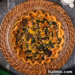 Overhead photo of a golden-brown Spinach Mushroom Quiche, perfectly baked and ready to slice.