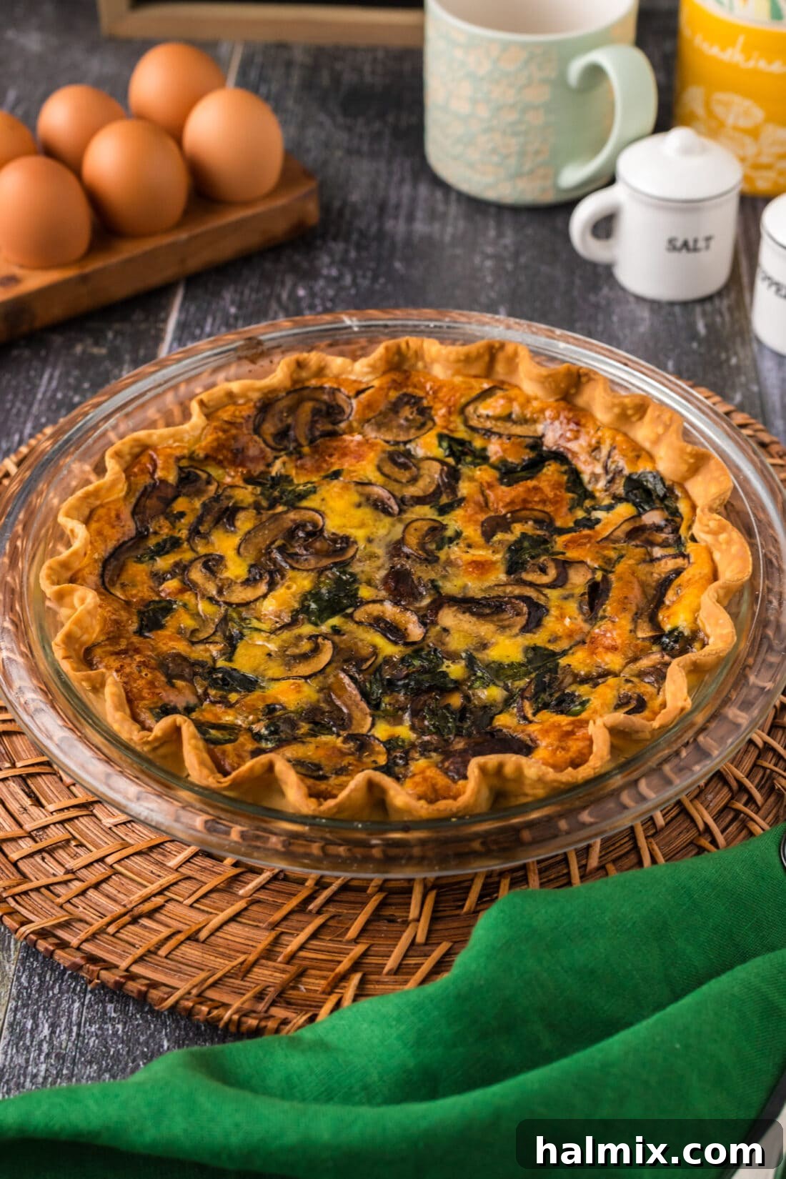 A beautifully presented Spinach Mushroom Quiche resting on a rustic wooden charger, ready to be sliced and served.