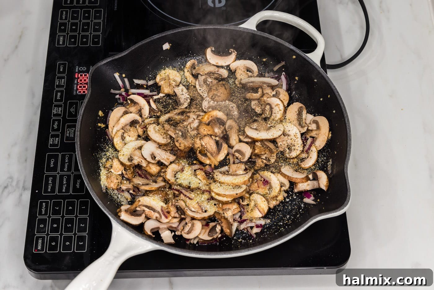 Sliced mushrooms being added to the skillet with the sautéed garlic and onion, ready to be seasoned and cooked.