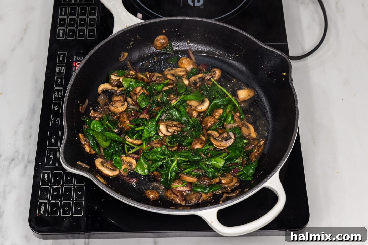 The fully sautéed spinach and mushroom mixture, cooked down and tender, in the skillet before being transferred out.