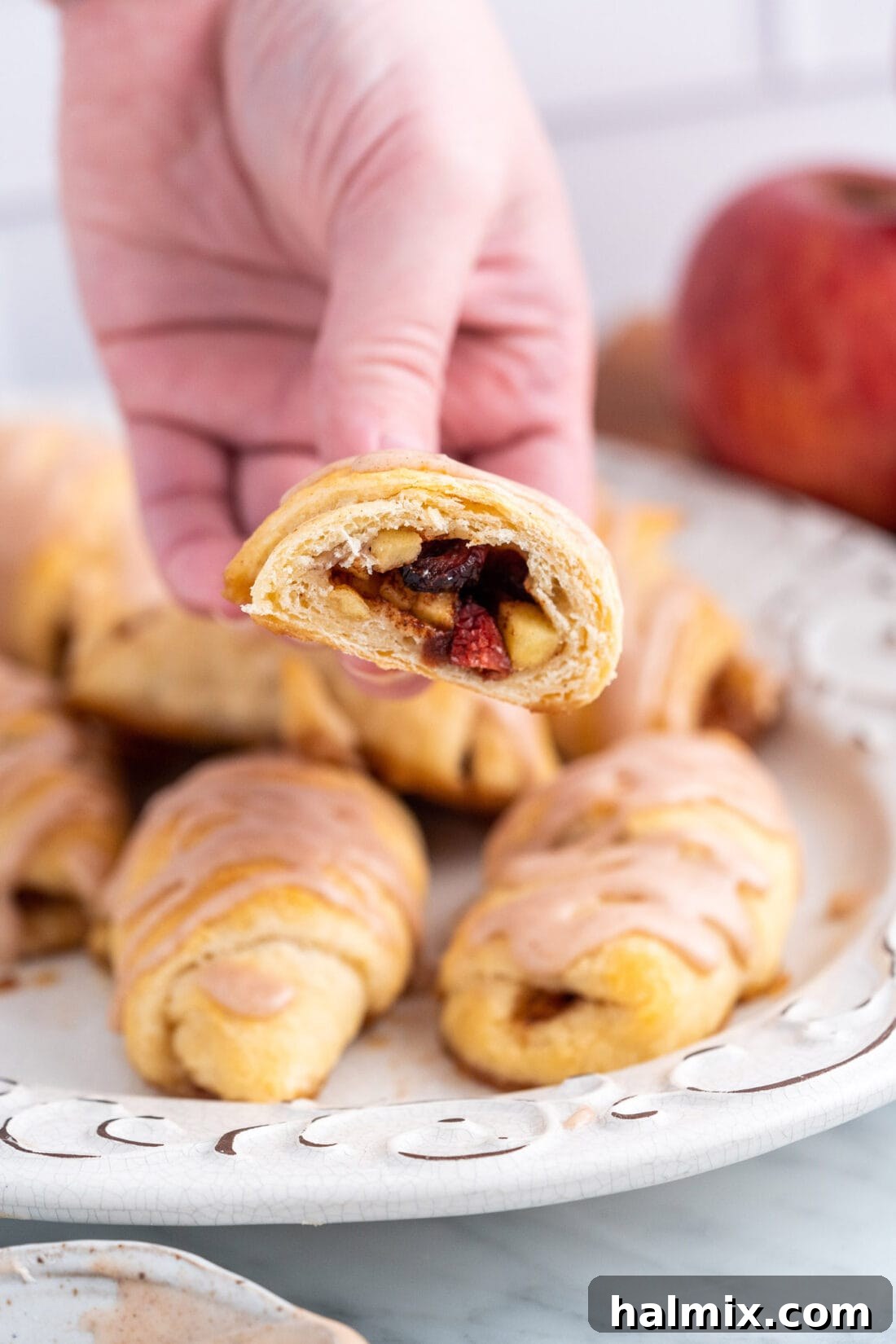 A hand reaching for a warm, glazed apple pie bite, highlighting its perfect snack size.