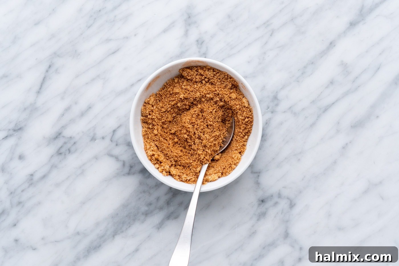 Close-up photo of brown sugar, cinnamon, and nutmeg blended together in a white bowl.