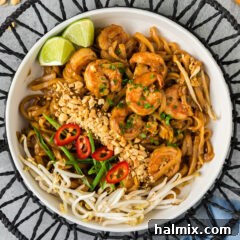 Bowl of Shrimp Pad Thai with chopped peanuts, bean sprouts, green onion and pepper on the side