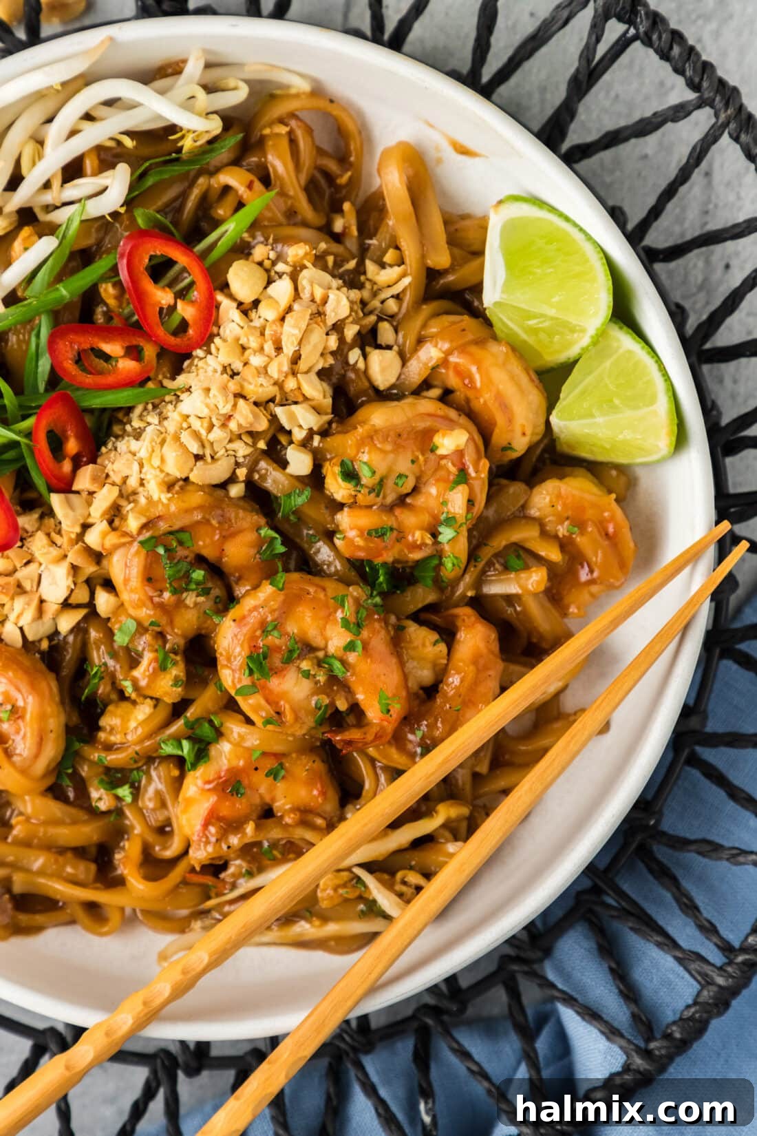 Vibrant Shrimp Pad Thai 3 Close-up view of a serving of Shrimp Pad Thai in a ceramic bowl, with chopsticks resting on the rim, showcasing the vibrant colors and textures of the dish.