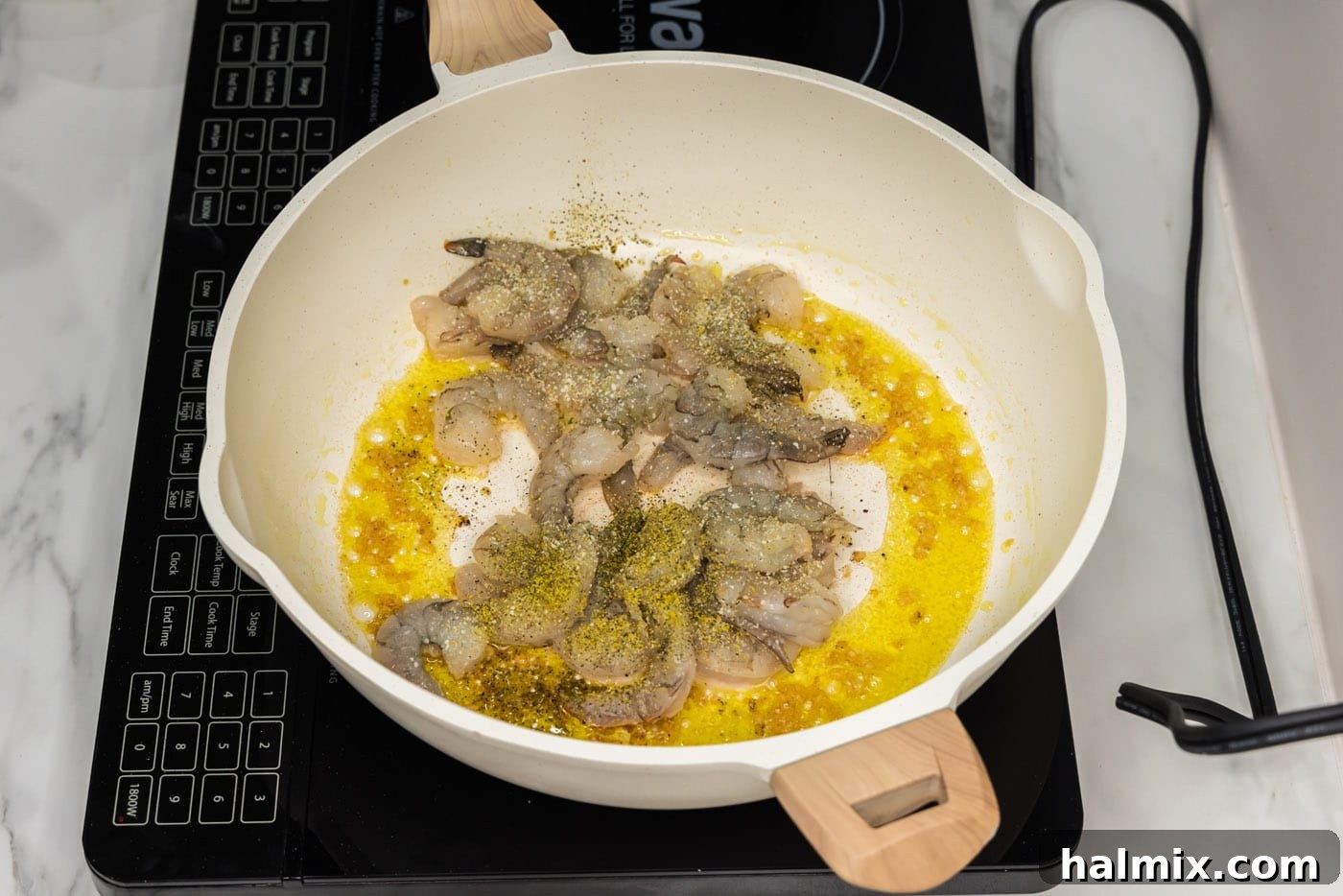 Raw shrimp and minced garlic cooking in a hot skillet with olive oil.