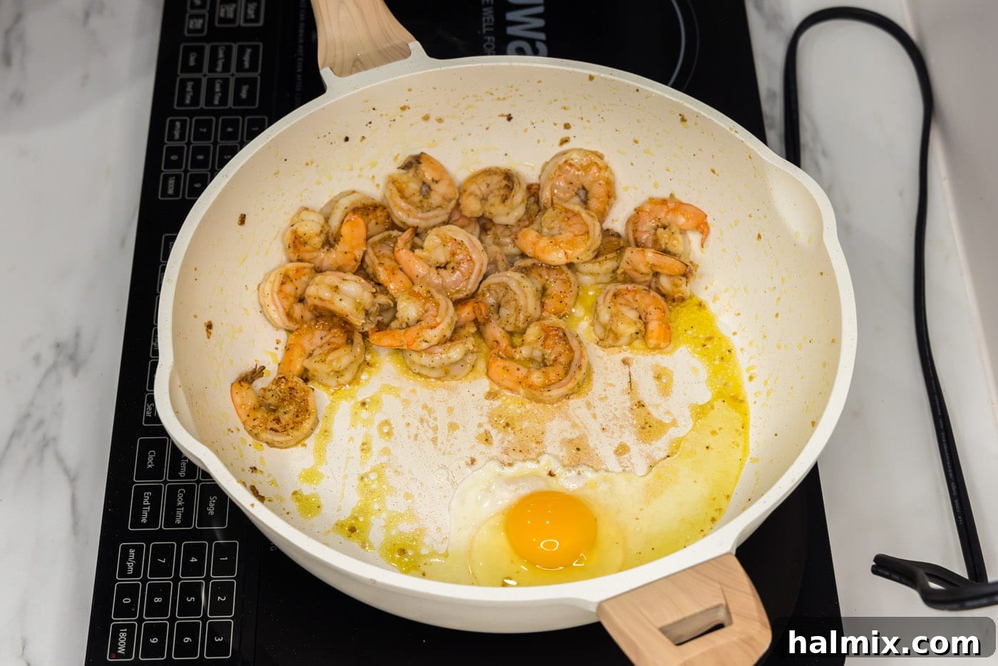 Vibrant Shrimp Pad Thai 7 A single egg cracking into a hot skillet next to sautéed shrimp.