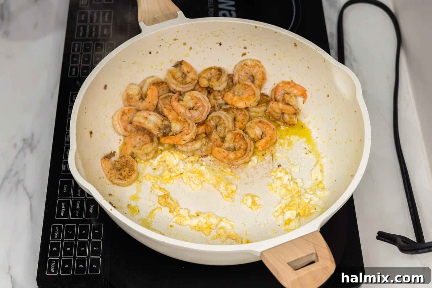 Scrambled egg and cooked shrimp mixed together in the skillet.