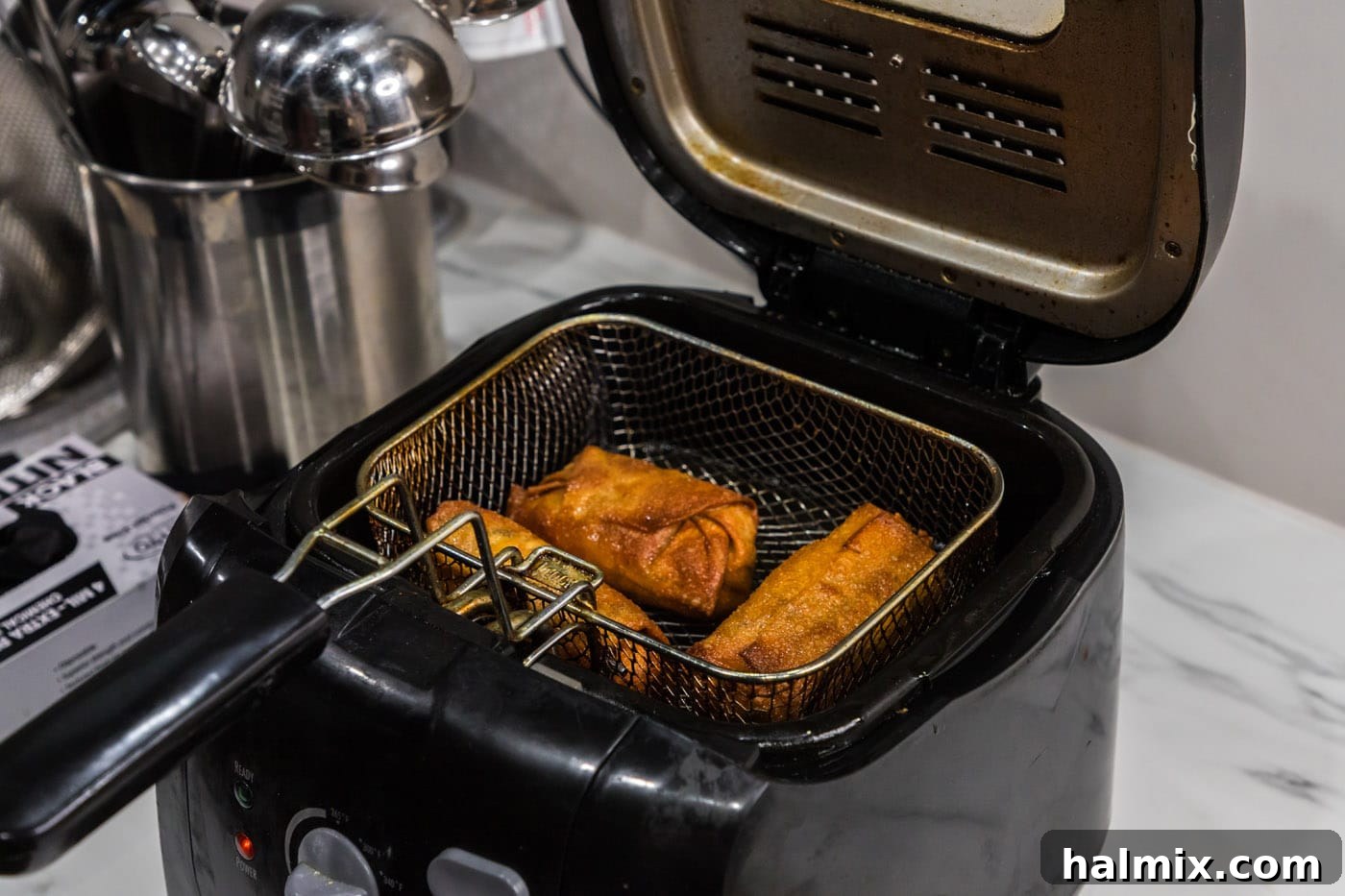 Crispy, golden brown Big Mac Egg Rolls in a deep fryer basket, just removed from the oil.
