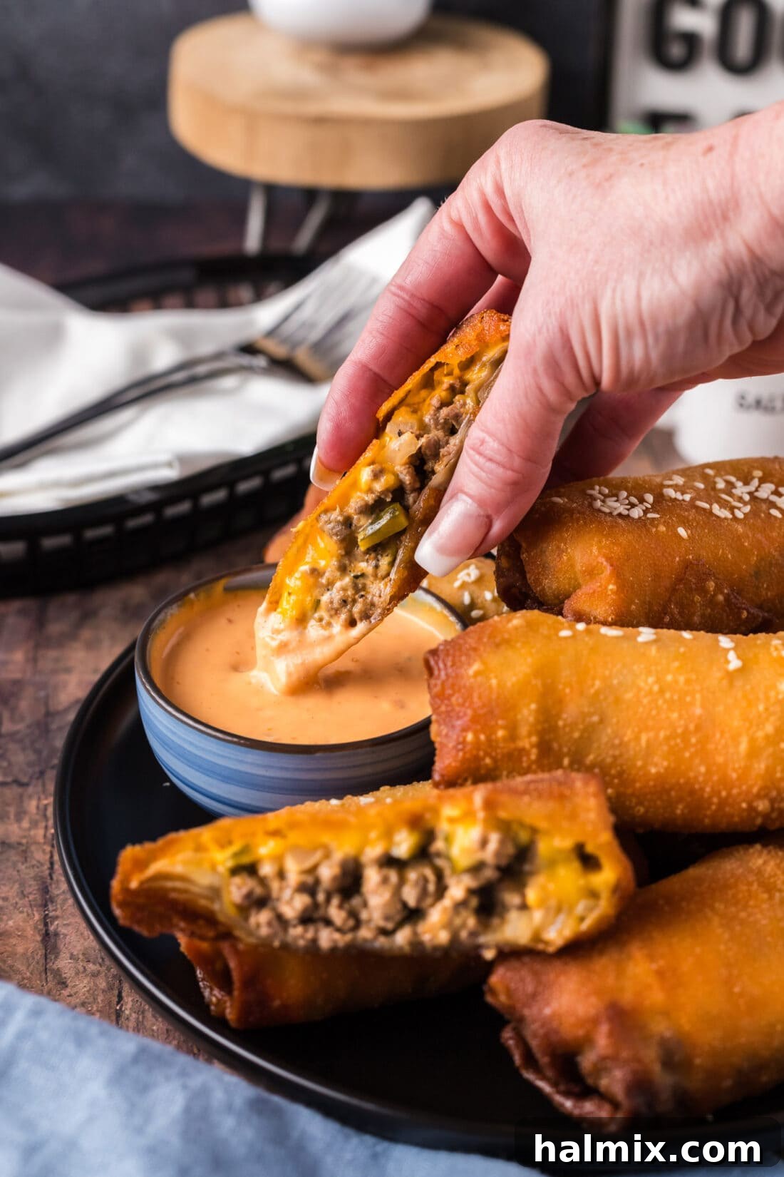 Half of a crispy Big Mac Egg Roll being dipped into a bowl of creamy Thousand Island dressing, ready to be enjoyed.