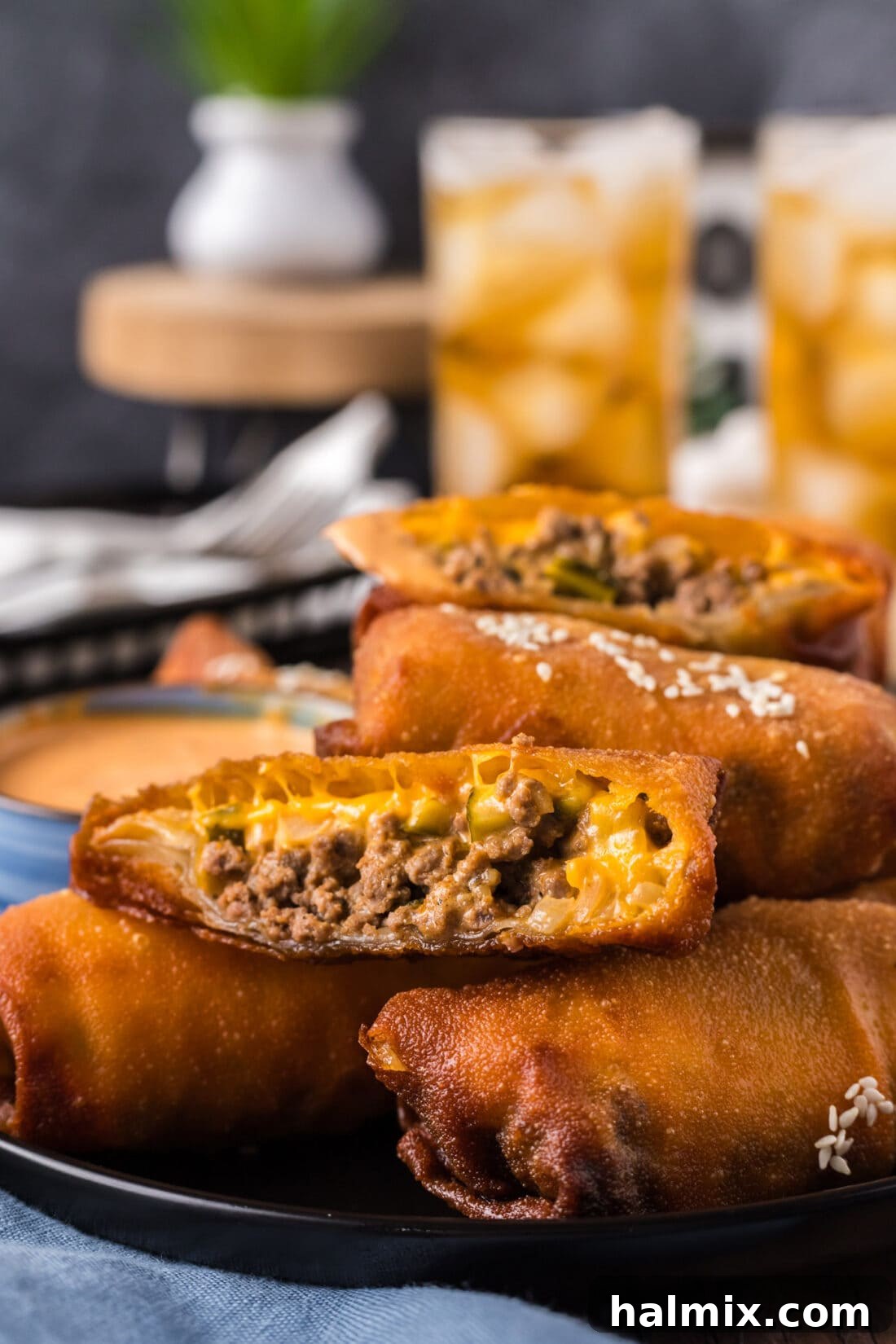 A Big Mac Egg Roll cut diagonally, revealing the flavorful filling, resting on top of other Big Mac Egg Rolls, ready to be served.