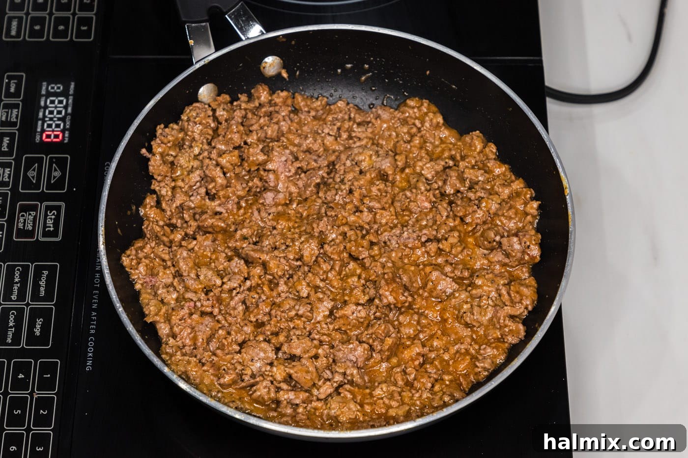 The ground beef mixture in a skillet, now combined with ketchup and mustard, ready for the next step.