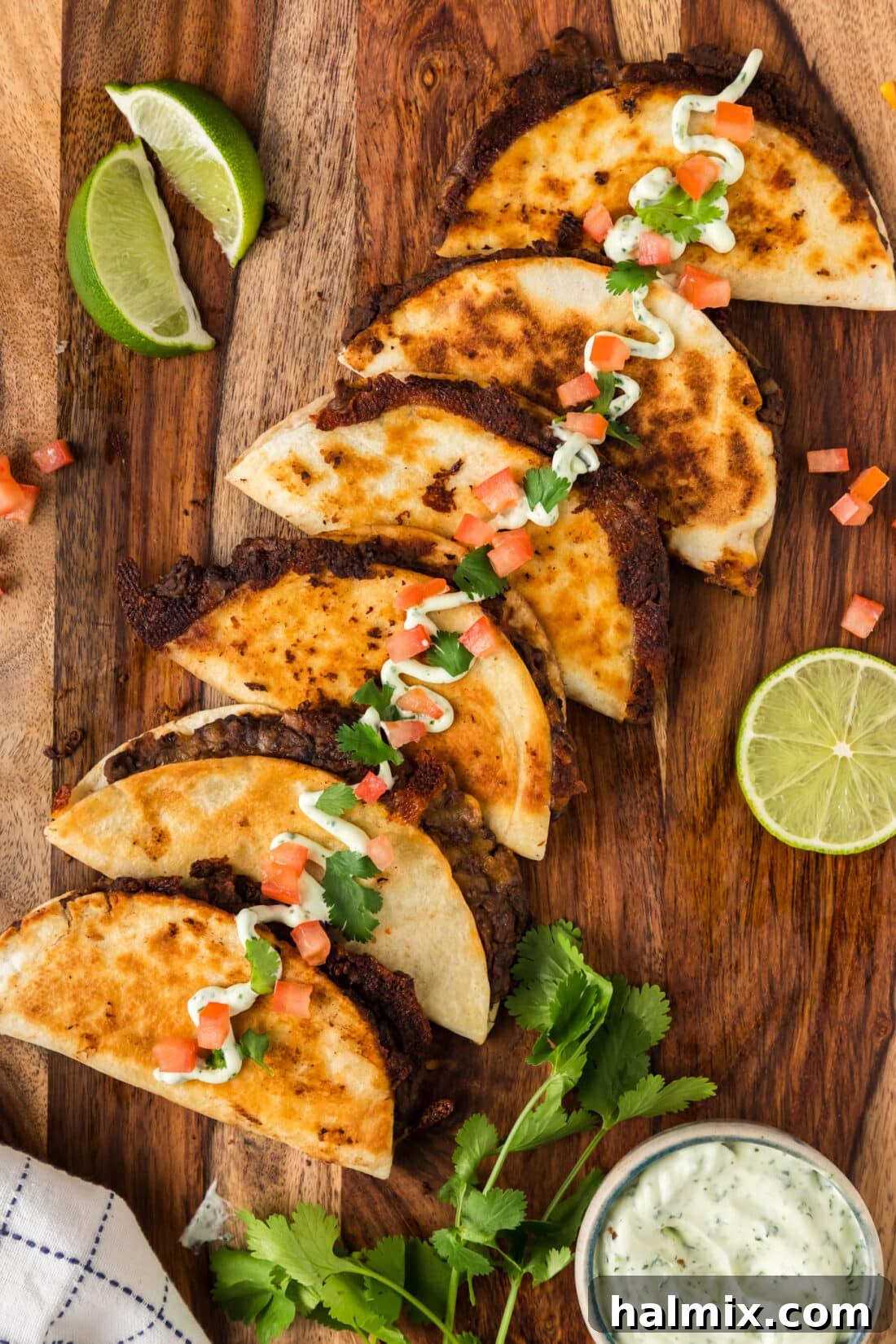 Black Bean Tacos on a wooden board topped with sour cream, tomatoes and cilantro