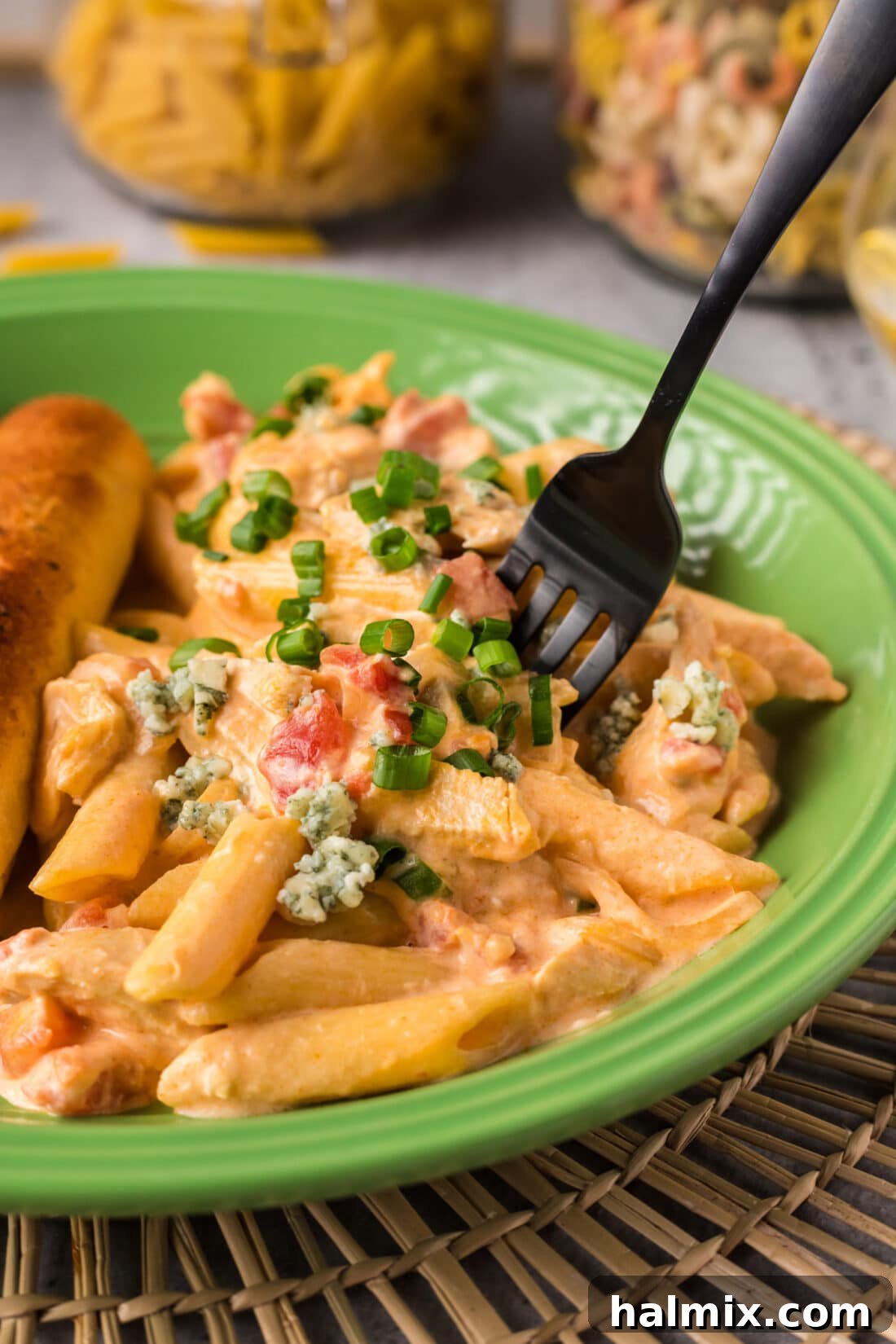A fork piercing a generous portion of creamy Buffalo Chicken Pasta on a white plate, ready to be enjoyed.