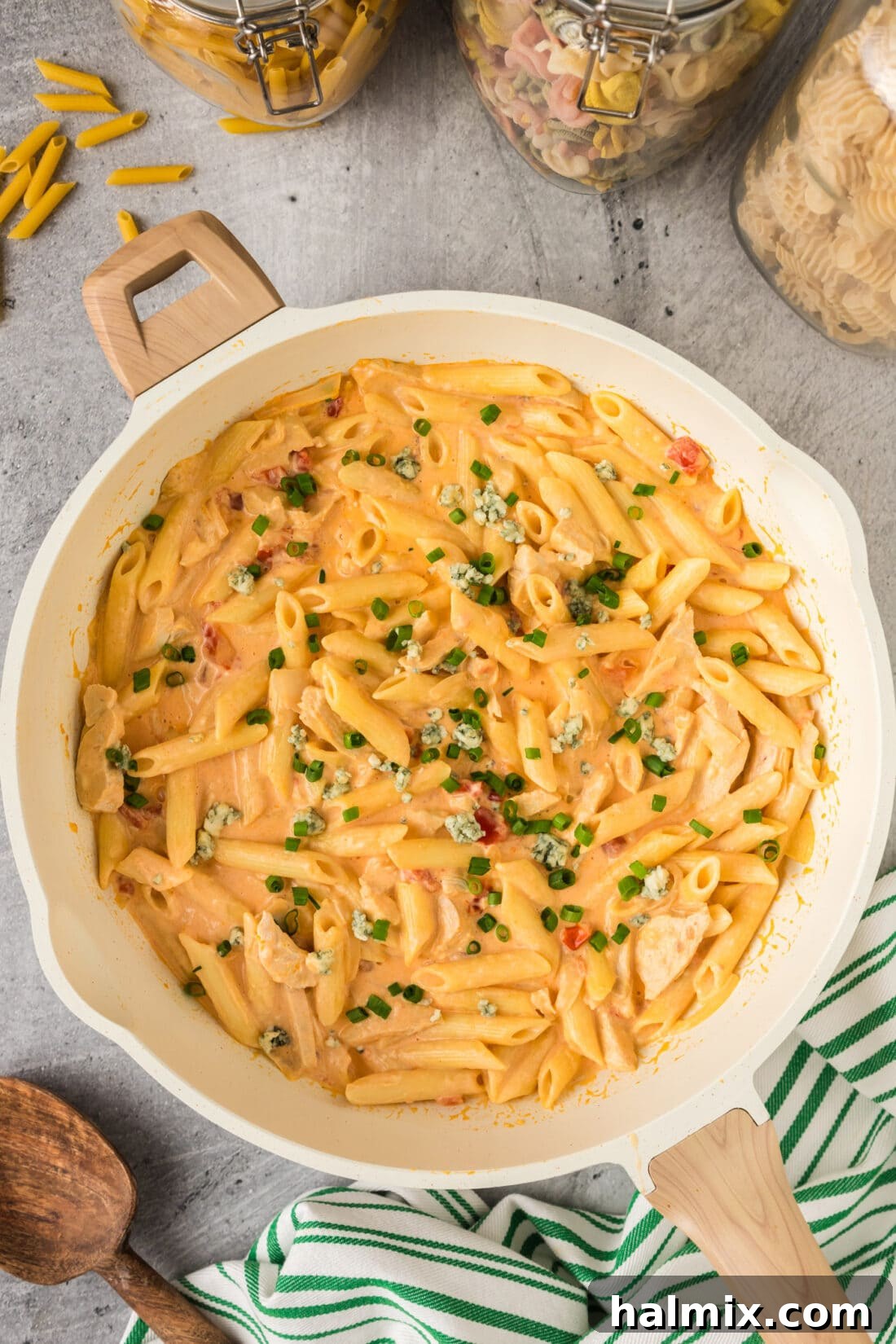 A large skillet filled with creamy and spicy Buffalo Chicken Pasta, garnished and ready to be served family-style.