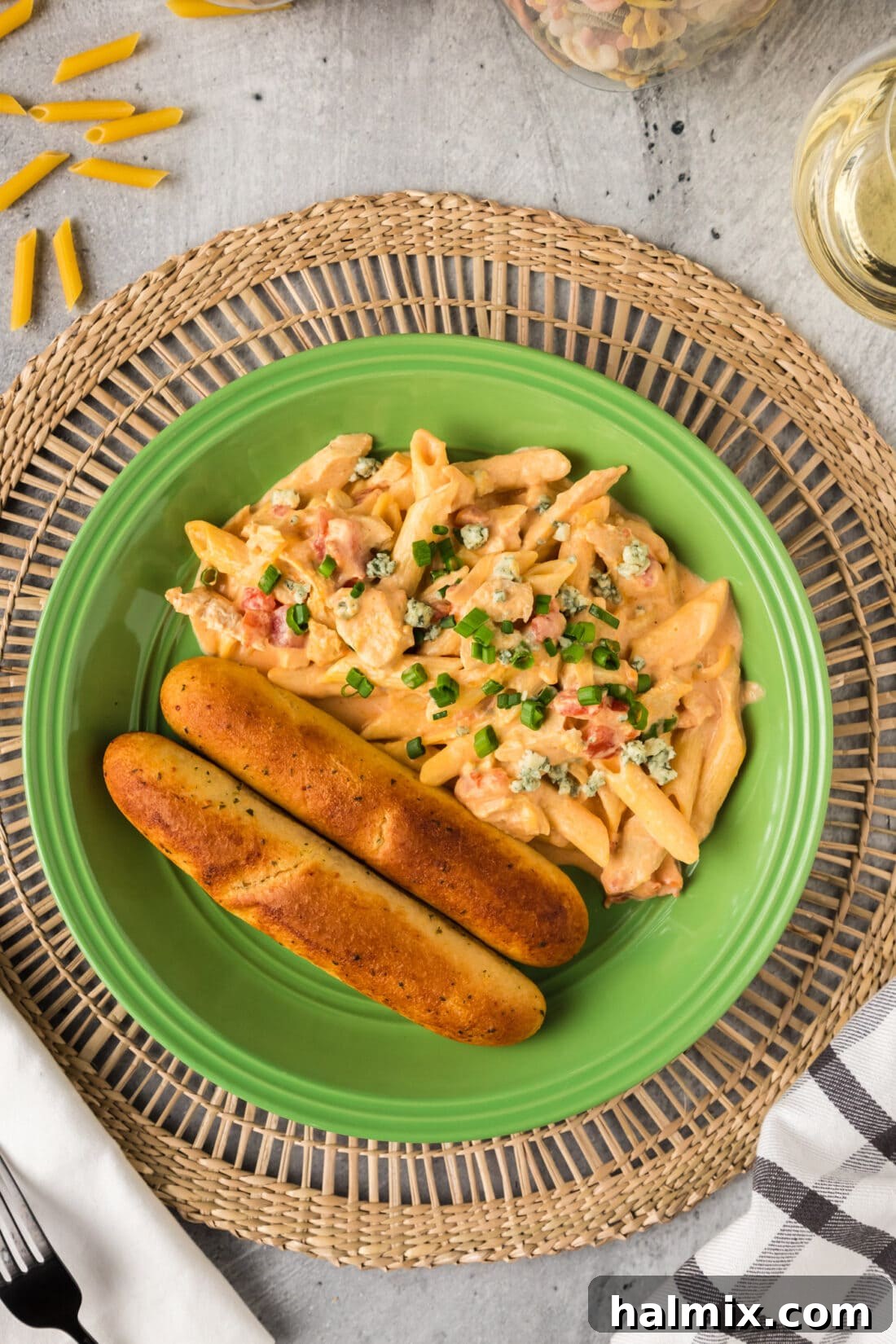 A plate of creamy Buffalo Chicken Pasta served with two breadsticks on the side, ready for a comforting meal.