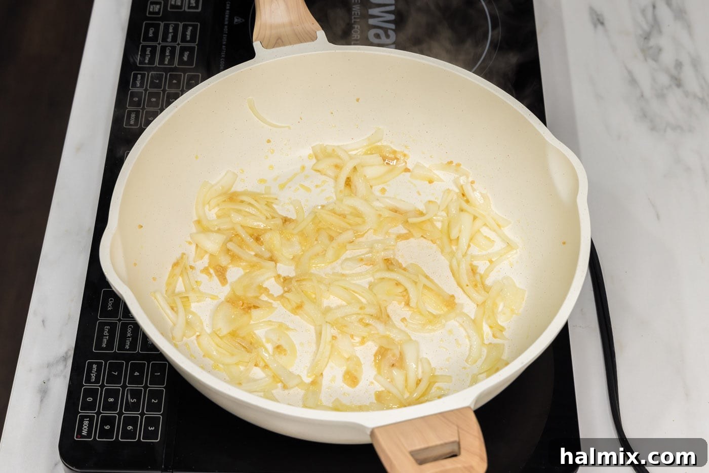 Minced garlic and sliced onions sizzling in olive oil in a skillet.